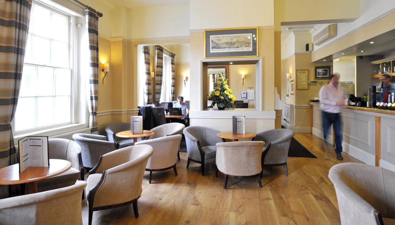 a man standing in a restaurant with tables and chairs at Royal Hotel in Bath